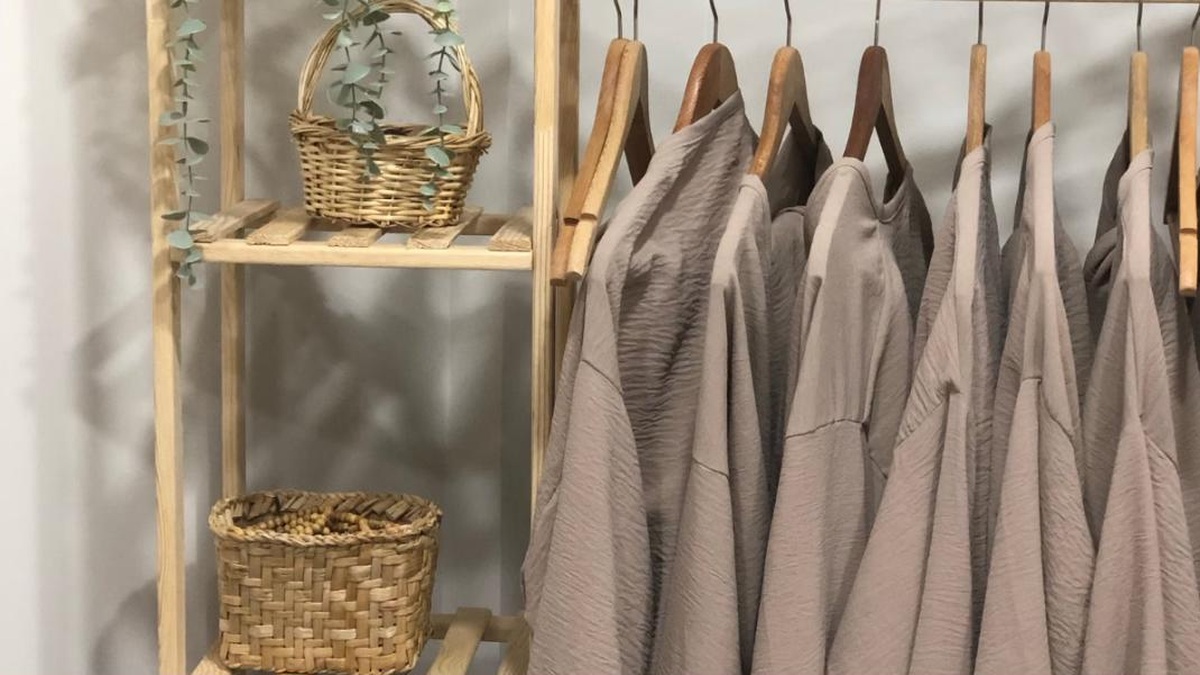 A freestanding wardrobe and open clothes rack against the wall of a small bedroom