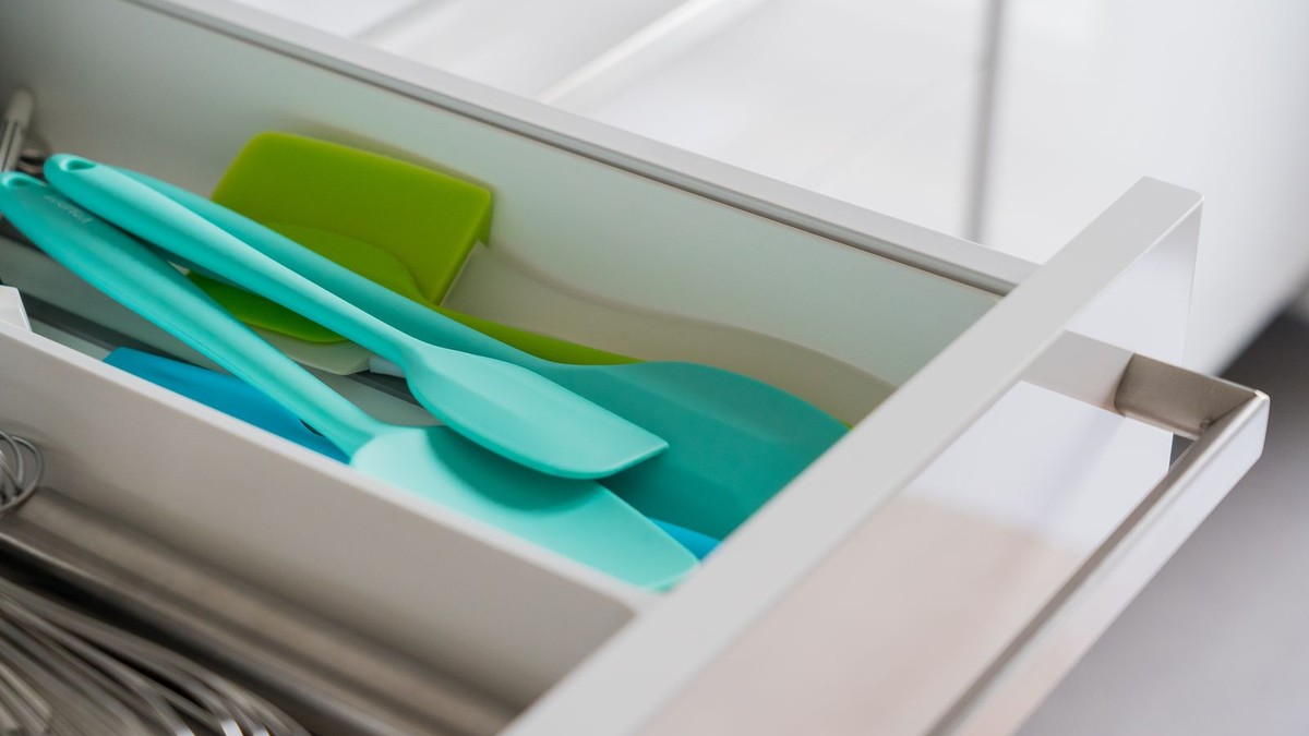A kitchen drawer neatly divided with a bamboo silverware tray and utensil organizers
