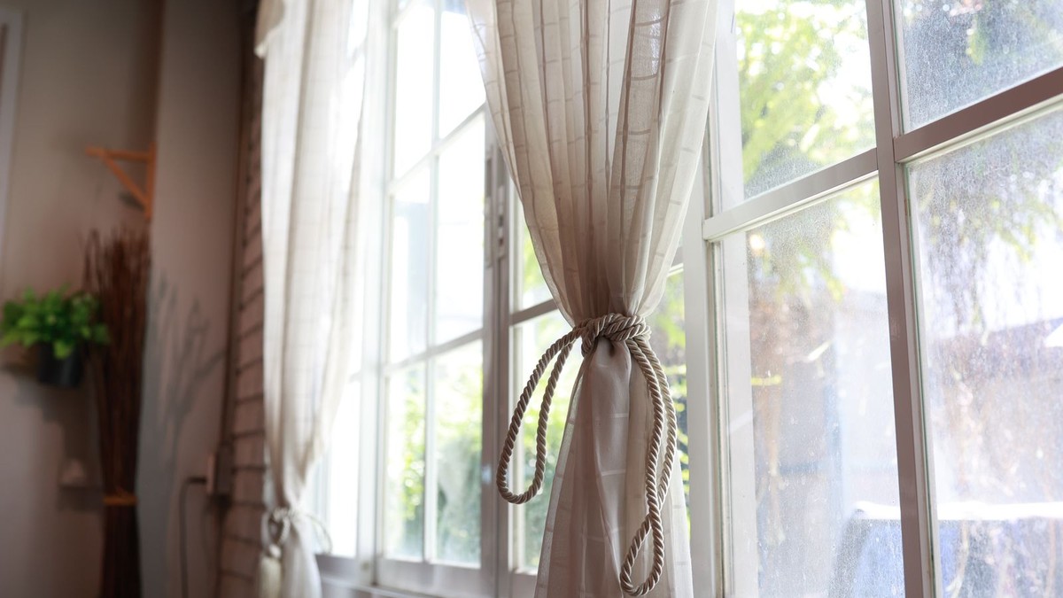 Curtains hung on a no-drill rod over a bright apartment window