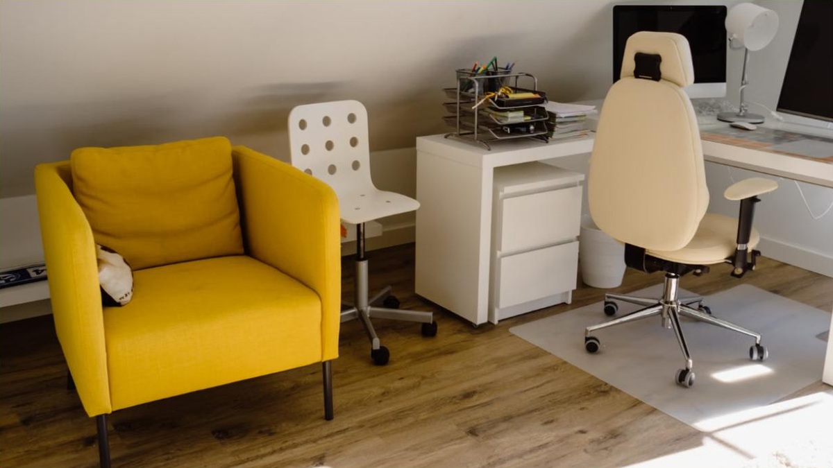 A compact armless office chair tucked under a small desk in a bright apartment nook