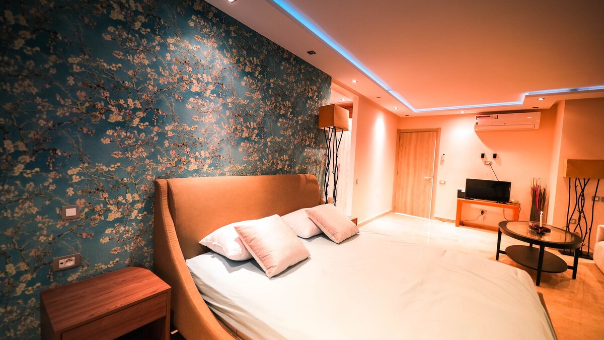 A rental bedroom accent wall covered in removable floral peel-and-stick wallpaper behind the bed