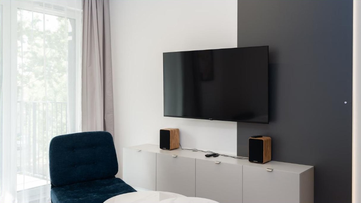 A compact media console TV stand under a wall-mounted TV in a small living room